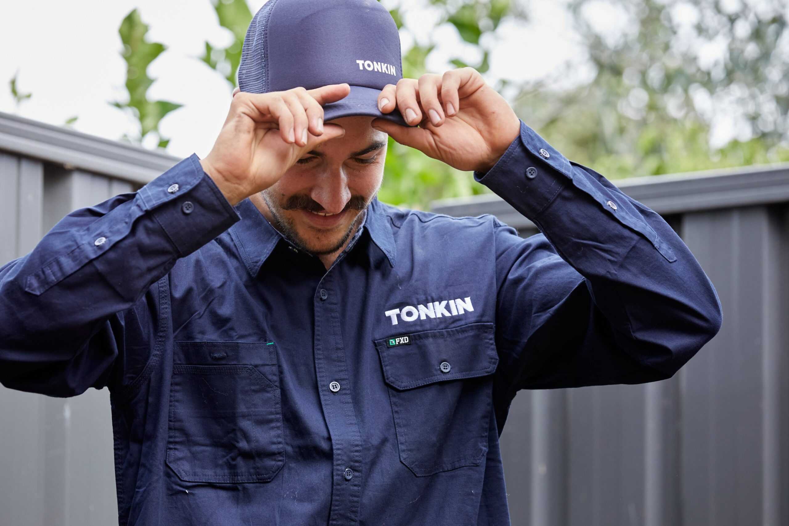 A Tonkin Employee holding his Tonkin baseball cap.